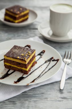 bir kafede beyaz tabakta çikolatalı üç kat kek parçası