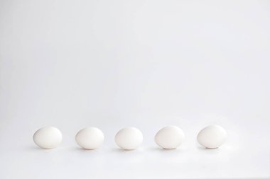 Beyaz bir arka plan üzerinde yatay olarak dizilmiş beyaz tavuk yumurtası
