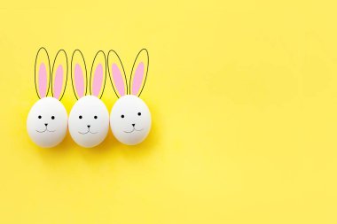 Üç komik sarı bir arka plan üzerinde çizilmiş Bunny tavuk yumurta