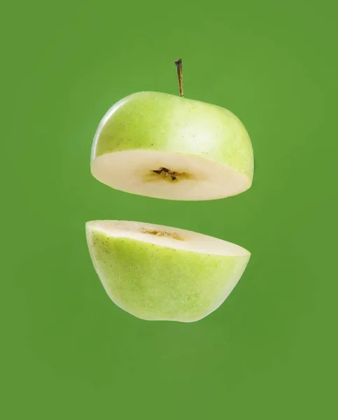 Cut green Apple in half on green background — Stock Photo, Image