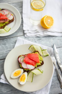 Ahşap tahta üzerinde Somon, Avokado, yumurta ve salatalık ile iki Tost sandviç.