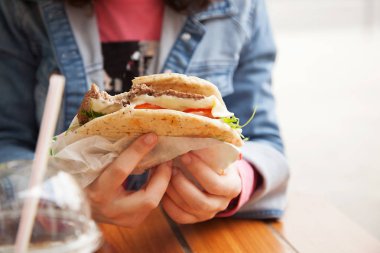 sokakta bir hamburger tutan eller