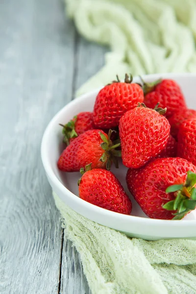Juicy ferske jordbær i en hvit plate på grå trebakgrunn, selektivt fokus – stockfoto
