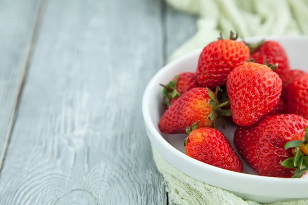 Juicy ferske jordbær i en hvit plate på grå trebakgrunn, selektivt fokus – stockfoto