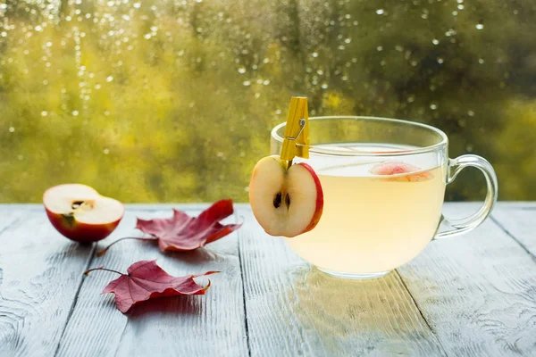 Csésze forró Apple ütés az esős őszi időjárás. Italt a fa asztalra az ablakon — Stock Fotó