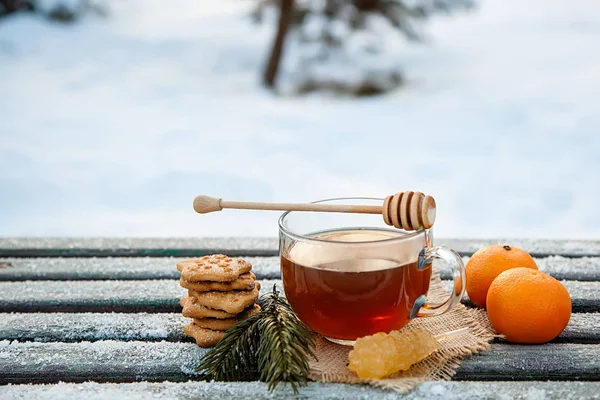 Csésze forró tea witn méz, mandarin és a cookie-k a téli erdőben. a Karácsonyi csendélet fogalma — Stock Fotó