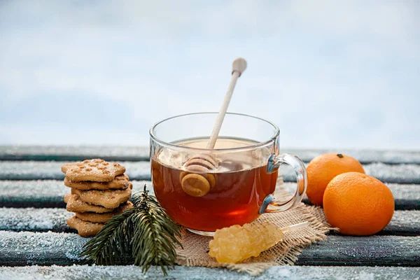 Csésze forró tea witn méz, mandarin és a cookie-k a téli erdőben. a Karácsonyi csendélet fogalma — Stock Fotó