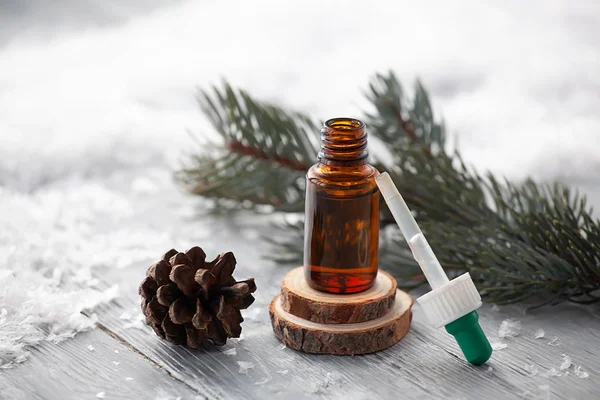 Çam aromalı yağ, karlı arka planda kozmetik şişelerdeki pipetle doğal olarak aromaterapi sağlar.