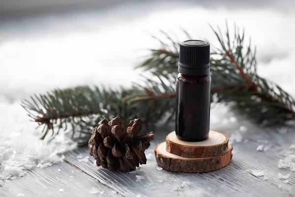 Çam aromalı yağ kozmetik şişelerinde kış karlı arka planda doğal aroma terapisi sağlar.