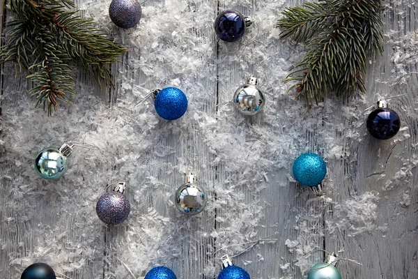 Brinquedos de Natal espalhados em uma mesa de madeira coberta de neve cinza. A vista de cima. Fundo de Natal . — Fotografia de Stock