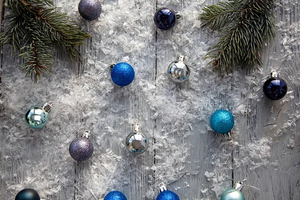 Bolas de Natal espalhadas em uma mesa de madeira coberta de neve cinza. A vista de cima. Fundo de Natal . — Fotografia de Stock