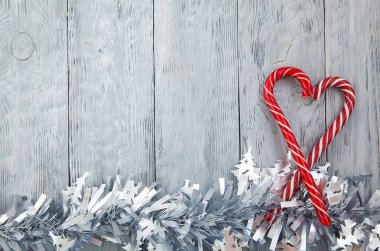 İki kırmızı lolipopun Noel kalbi, ahşap gri bir arka planda, şenlikli bir dekorasyonla. Noel arkaplanı, üst görünüm ve kopyalama alanı