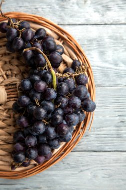 Yuvarlak bir tepside olgun, koyu bir üzüm yığını. Üst görünüm ve kopyalama alanı