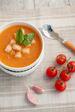 Masada vişneli domates dalıyla beyaz bir kasede domates kremalı çorba. Yukarıdan manzara. İtalyan çorbası.