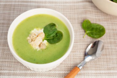 Beyaz kasede ıspanak yapraklı yeşil kremalı çorba. Tepeden manzara. Sağlıklı bir yaşam için lezzetli ıspanak çorbası.
