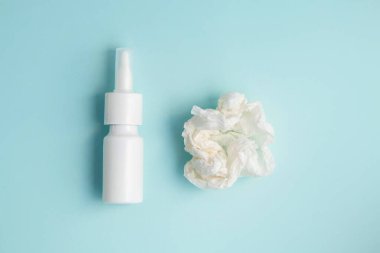 Burun spreyi ve buruşuk mendiller pembe arka planda, üst tarafta..