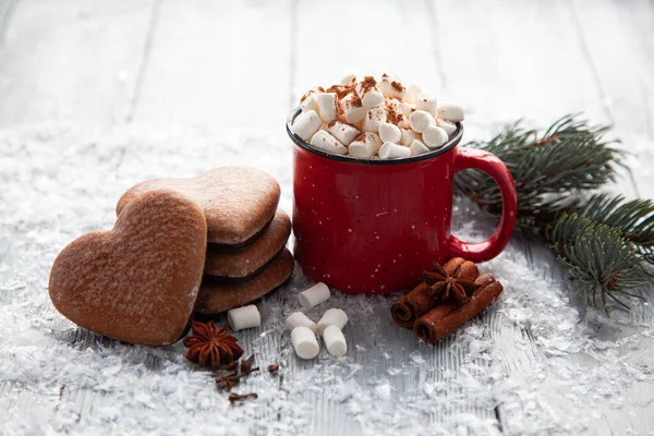 Чашка горячего какао с зефиром и рождественскими пряниками в виде сердца на снежном деревянном фоне. — стоковое фото