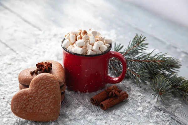 Tasse heißer Kakao mit Marshmallows und weihnachtlichem Lebkuchen in Herzform auf schneebedecktem Holzgrund. — Stockfoto