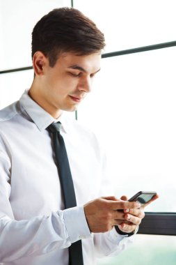 Telefonunu kullanarak genç yakışıklı işadamı portresi.