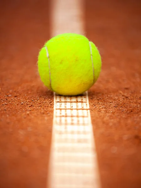 Egy sárga teniszlabda az agyag udvarán fekszik. — Stock Fotó