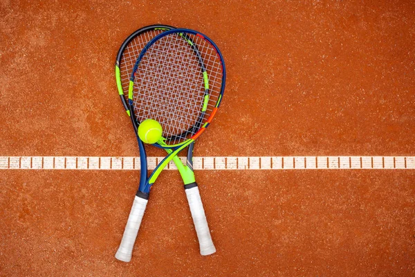 Top view of two tennis rackets and yellow tennis ball lie on the — Stock Photo, Image