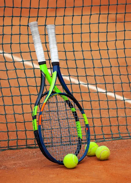 Tennis rackets and balls leaned against the net. — Stock Photo, Image