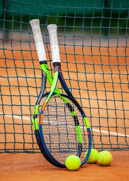 Tennis rackets and balls leaned against the net. — Stock Photo, Image