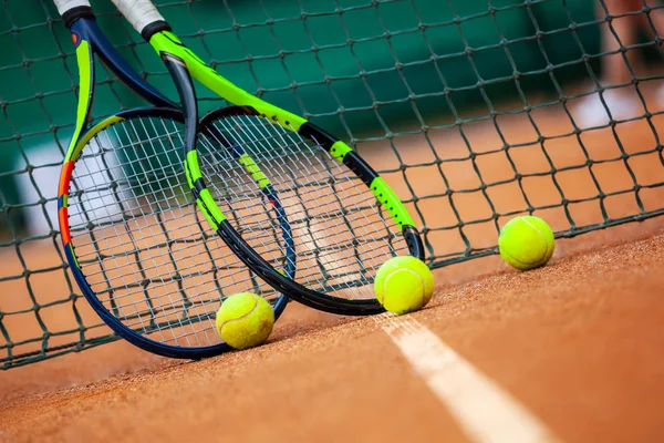 Tennis rackets and balls leaned against the net. — Stock Photo, Image