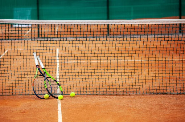 Tennis rackets and balls leaned against the net. — Stock Photo, Image