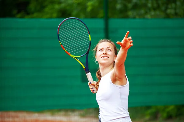 Junge Tennisspielerin serviert. — Stockfoto