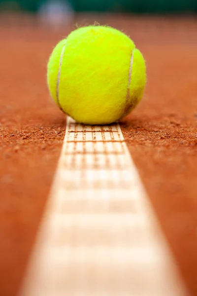 Egy sárga teniszlabda az agyag udvarán fekszik. — Stock Fotó