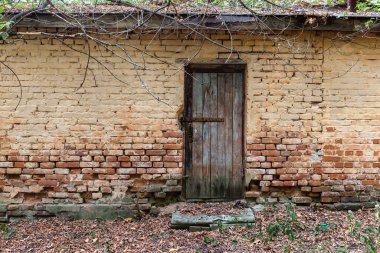 Ahşap kapılı ve tuğladan duvarı olan eski binanın yakınına..