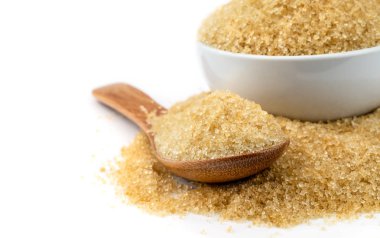 beyaz zemin üzerine tahta kaşıkla kahverengi şeker kamışı.