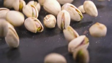 Antep fıstığı ağır çekim otantik siyah yapılandırılmış yüzeye düşüyor. Atış kapatın