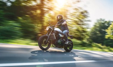Modern scrambler motosiklet üzerinde bir dağ orman yol hızlı hızlı sürme. Bir motosiklet Tur yolculuğa boş yol sürüş eğleniyor. Boşaltmak için bireysel metin.