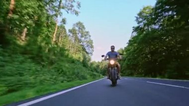 Modern özel scrambler motosiklet sürme - sollama ve eylemleri oyma bir orman yolu üzerinde. Bir motosiklet Tur yolculuğa boş yol sürüş eğleniyor. 4k Video.