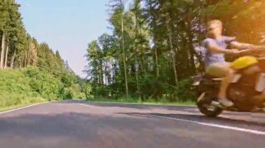 Modern özel scrambler motosiklet sürme - sollama ve eylemleri oyma bir orman yolu üzerinde. Bir motosiklet Tur yolculuğa boş yol sürüş eğleniyor. 4k Video.