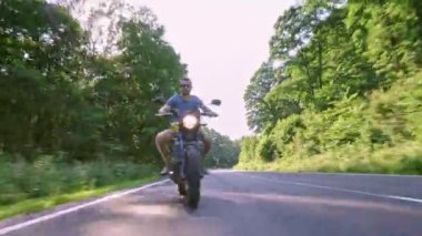 Modern özel scrambler motosiklet sürme - sollama ve eylemleri oyma bir orman yolu üzerinde. Bir motosiklet Tur yolculuğa boş yol sürüş eğleniyor. 4k Video.