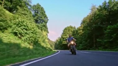 Modern özel scrambler motosiklet sürme - sollama ve eylemleri oyma bir orman yolu üzerinde. Bir motosiklet Tur yolculuğa boş yol sürüş eğleniyor. 4k Video.