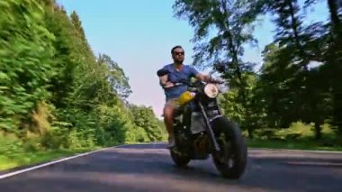 Modern özel scrambler motosiklet sürme - sollama ve eylemleri oyma bir orman yolu üzerinde. Bir motosiklet Tur yolculuğa boş yol sürüş eğleniyor. 4k Video.