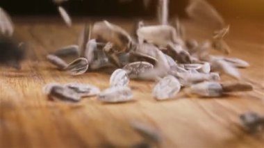 Birçok tohum ahşap masaya döküldü. Ağır çekimde kameraya doğru kayar.