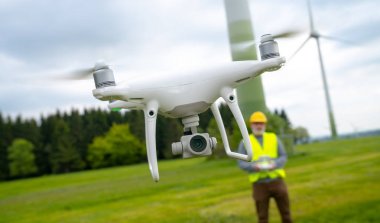 Rüzgar türbinini denetleyen inşaat işçisi tarafından işletilen drone, drone ile uçuyor.