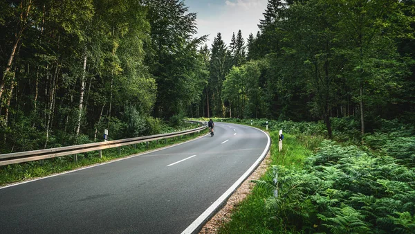 Cykel på lång kurvig skogsväg i alpina berg — Stockfoto