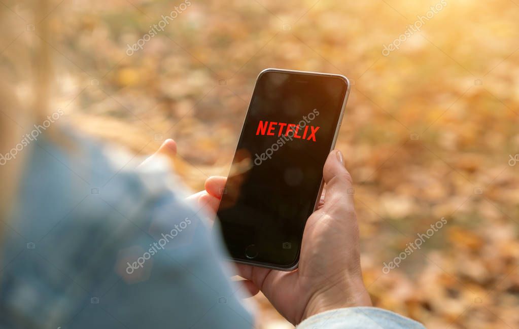 AACHEN, GERMANY - 31. August 2019 : Netflix app on Apple iPhone. Young man is browsing the movie video library what to watch.