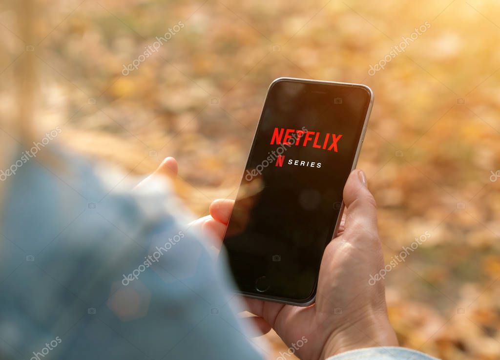 AACHEN, GERMANY - 31. August 2019 : Netflix app on Apple iPhone. Young man is browsing the movie video library what to watch.