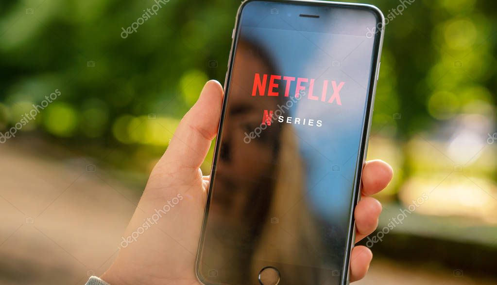AACHEN, GERMANY - 31. August 2019 : Netflix app on Apple iPhone. Young man is browsing the movie video library what to watch.
