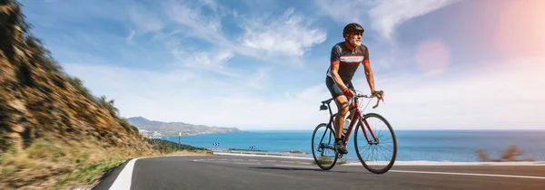 Adulto maduro en una bicicleta de carreras escalando la colina en el Mediterráneo — Foto de Stock