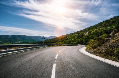Güneşli bir yaz gününde ufka giden boş uzun dağ yolu