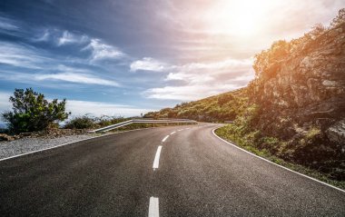 Güneşli bir yaz gününde ufka giden boş uzun dağ yolu