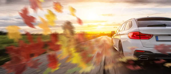 Rask bil på høstlandskapsvei ved solnedgang – stockfoto